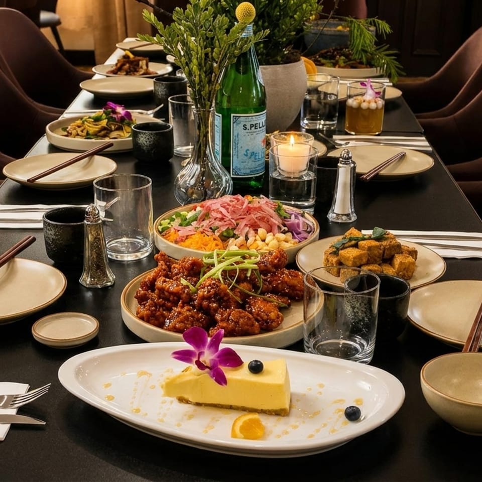 A long dining table set with multiple dishes, including dessert, and chairs in a restaurant.