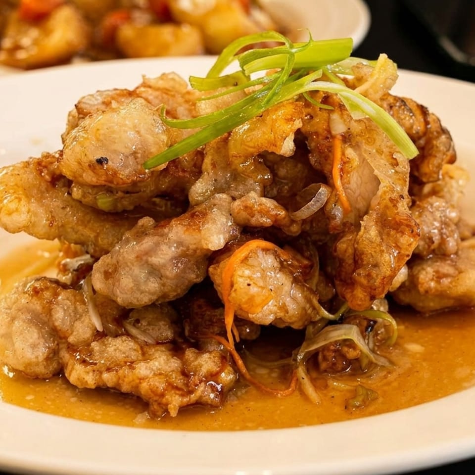Crispy fried chicken or pork in a light sauce, garnished with green onions and shredded carrots.